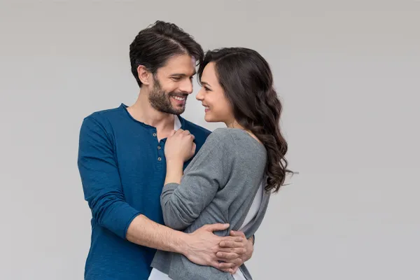 Erectile-Dysfunction-Doctor A man in a blue shirt embracing a woman in a gray shirt smiles due to his successful erectile dysfunction care from Julie Kane, NP of Trua Health & Wellness in Alaska.