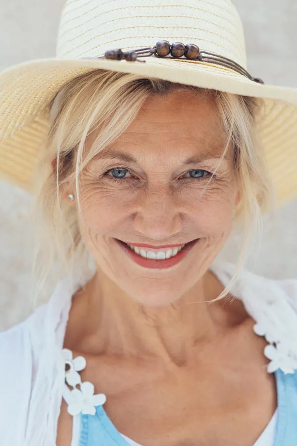 Menopause-Treatment A beautiful, smiling older woman with blonde hair and a sunhat, happy with menopause treatment from Julie Kane, NP of Trua Health & Wellness in Alaska.