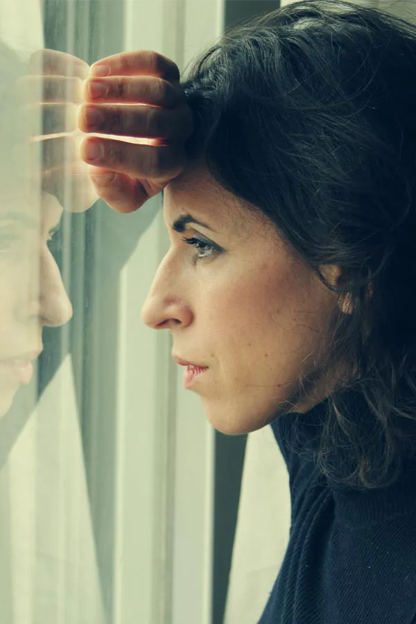 PCOS-Treatment A brunette woman in a thin dark turtleneck looks out the window with a serious expression, suffering from PCOS. Get treatment for Polycistic Ovarian Syndrome/PCOS from Julie Kane, NP of Trua Health & Wellness in Alaska.