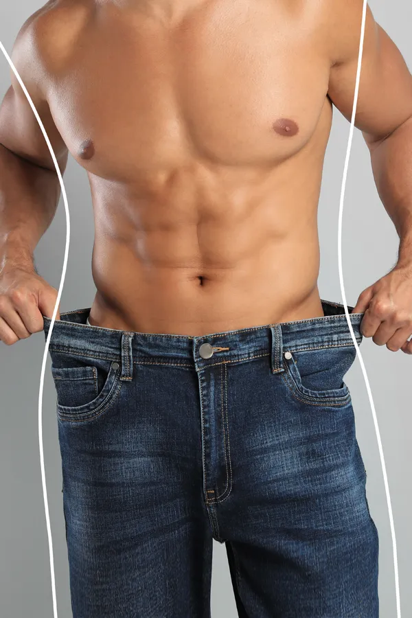 Semaglutide-Weight-Loss-Treatment A strong shirtless man in jeans holds the waistlines of his too-big jeans to show the success of semaglutide weight loss from Julie Kane, NP of Trua Health & Wellness in Alaska.
